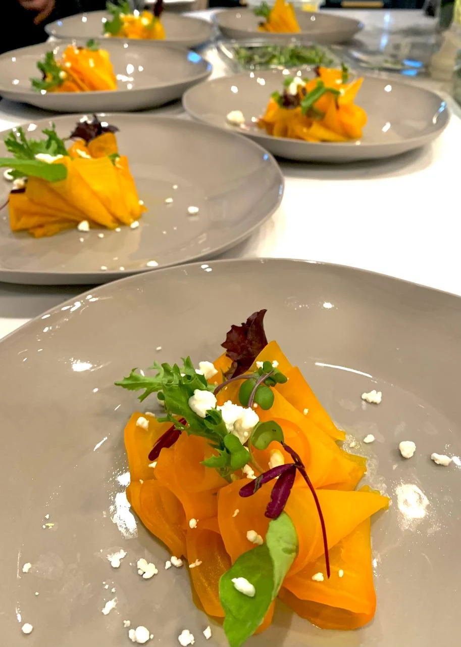 Individually plated dishes with golden ribbons and fresh greens, prepared by XIM Catering